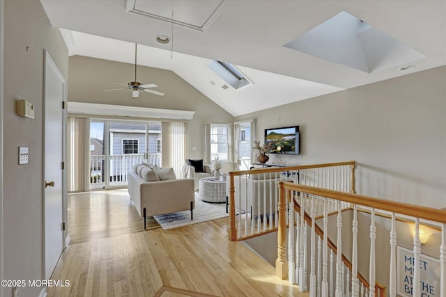 hallway with high vaulted ceiling, light wood finished floors, an upstairs landing, and attic access