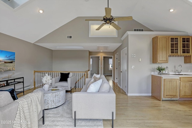 living area featuring a baseboard heating unit, baseboards, visible vents, and light wood finished floors