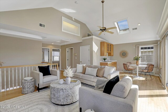 living room with high vaulted ceiling, light wood-type flooring, and visible vents