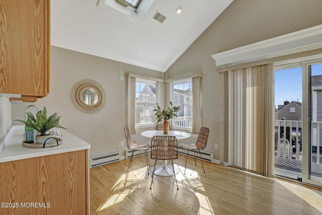 dining room with light wood finished floors, a baseboard radiator, visible vents, a baseboard heating unit, and lofted ceiling with skylight