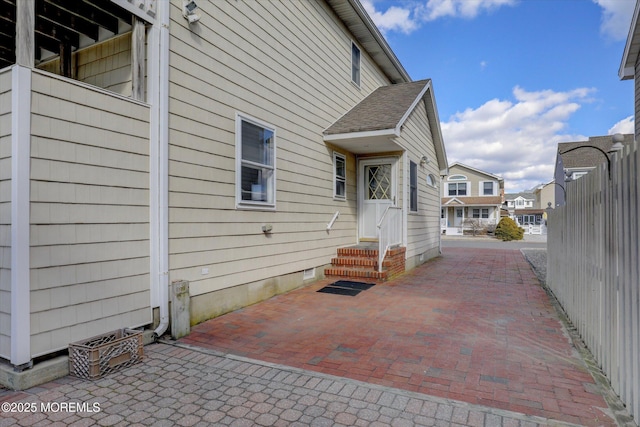 view of side of home featuring entry steps, crawl space, roof with shingles, and a patio