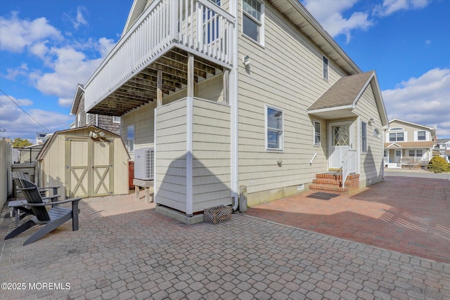 rear view of property featuring a storage shed, a patio, an outdoor structure, and cooling unit