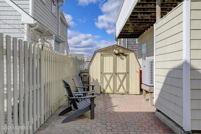 view of patio with an outbuilding, fence, and a storage shed