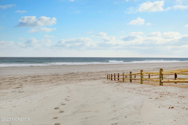 property view of water with fence and a view of the beach