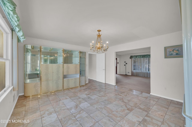 empty room with baseboards and a notable chandelier