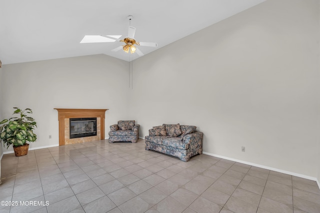 unfurnished room with lofted ceiling with skylight, a glass covered fireplace, a ceiling fan, baseboards, and tile patterned floors