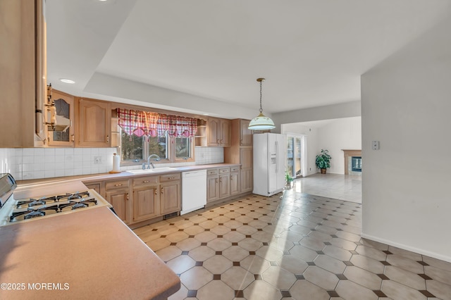 kitchen with tasteful backsplash, plenty of natural light, white appliances, and a sink