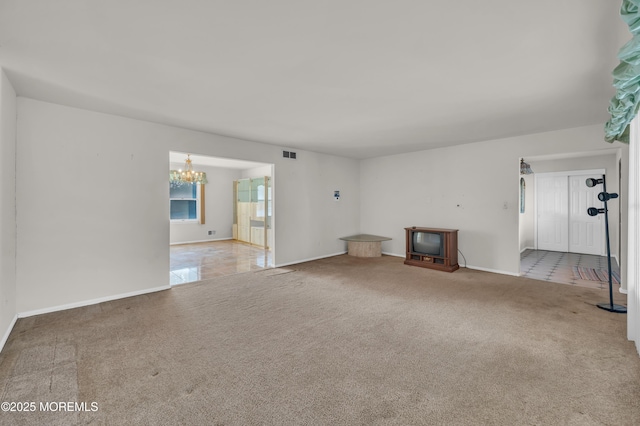 unfurnished living room featuring an inviting chandelier, baseboards, visible vents, and carpet flooring