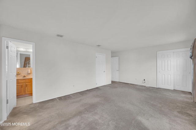 unfurnished bedroom with visible vents, carpet flooring, and ensuite bathroom