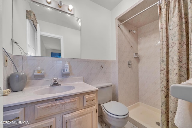 bathroom with tile walls, a shower stall, toilet, and vanity