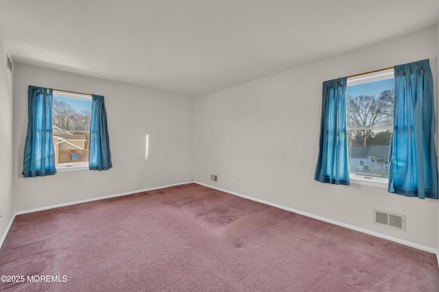 empty room with plenty of natural light, carpet flooring, visible vents, and baseboards