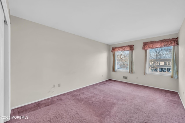 empty room featuring carpet flooring, visible vents, and baseboards