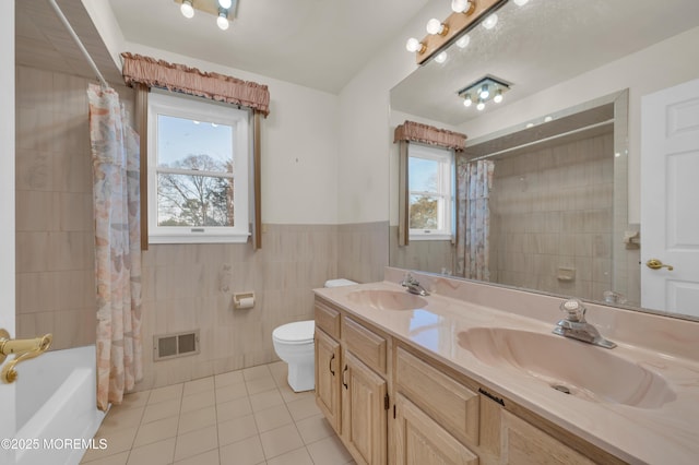 bathroom featuring visible vents, a sink, tile walls, and tile patterned floors