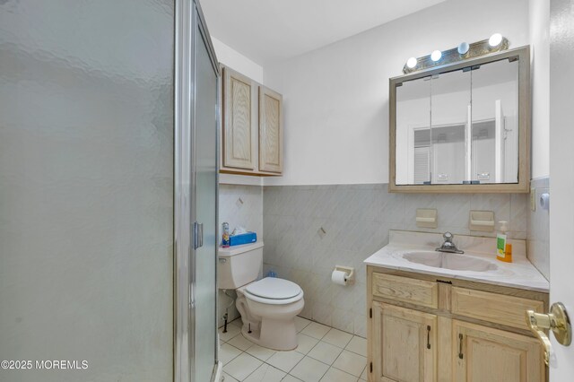 bathroom with a stall shower, toilet, tile patterned floors, vanity, and tile walls