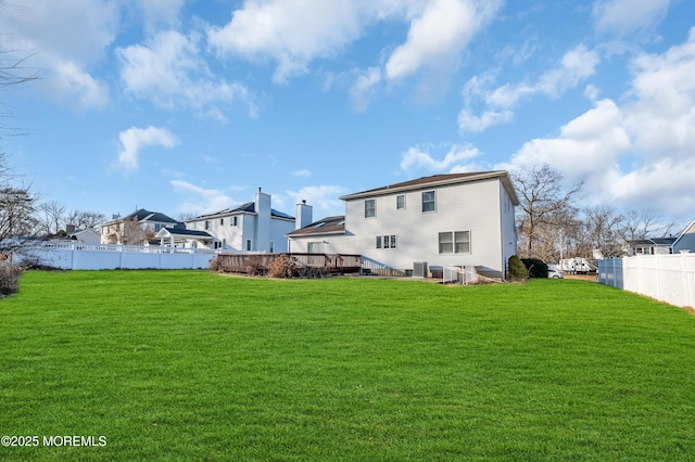 back of house featuring fence, a deck, and a lawn