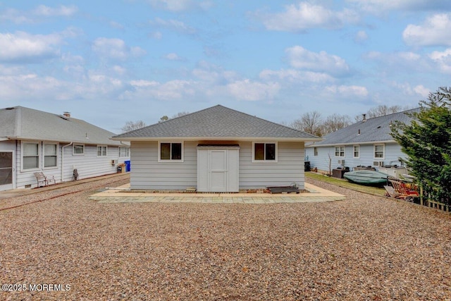 back of house featuring roof with shingles and an outdoor structure