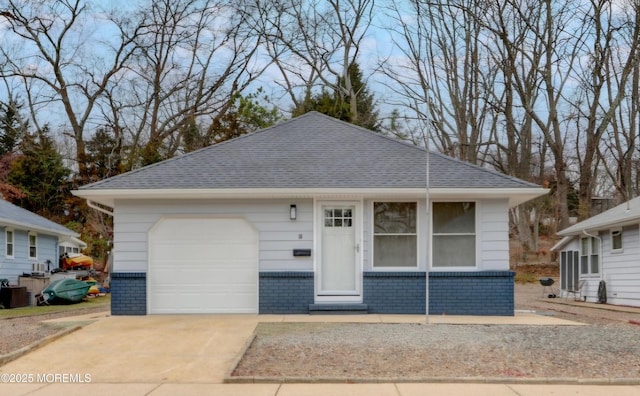 view of front of home featuring a garage, brick siding, and a shingled roof