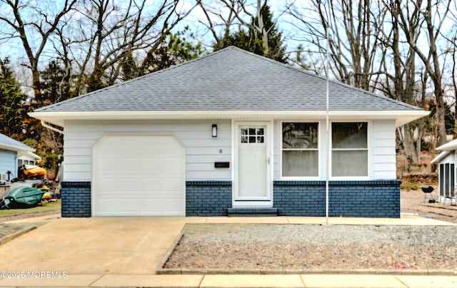 view of front of house with a garage, brick siding, roof with shingles, and concrete driveway