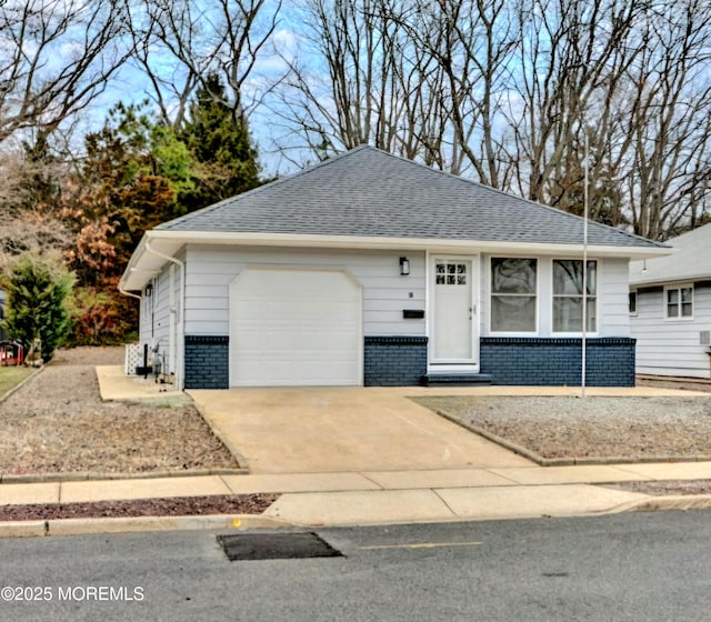 single story home featuring a garage, driveway, and roof with shingles