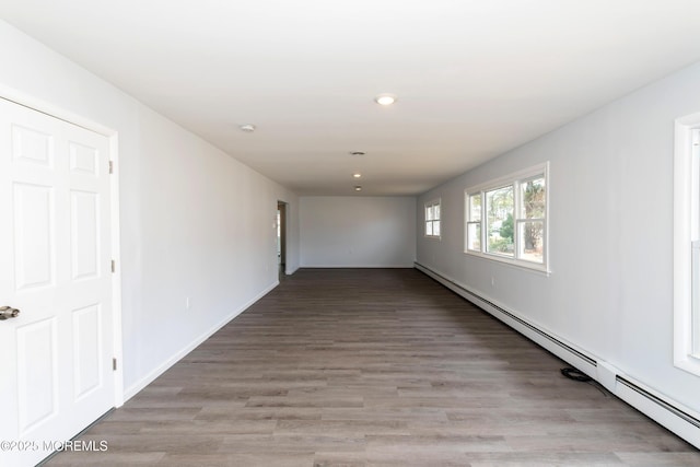 unfurnished room with baseboards, baseboard heating, light wood-type flooring, and recessed lighting