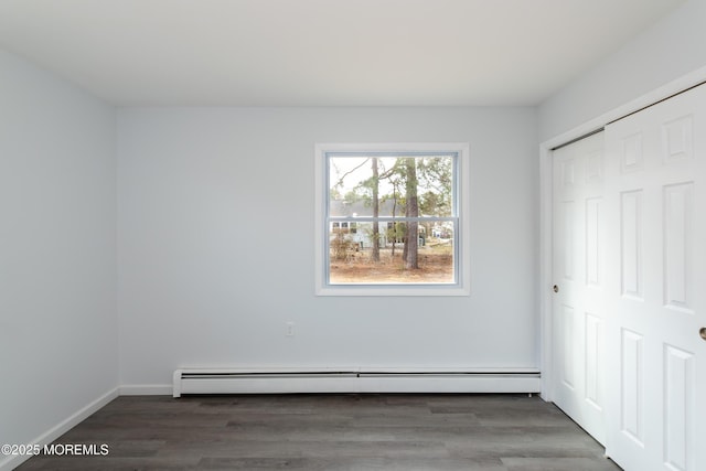 unfurnished bedroom with baseboards, a closet, a baseboard heating unit, and wood finished floors