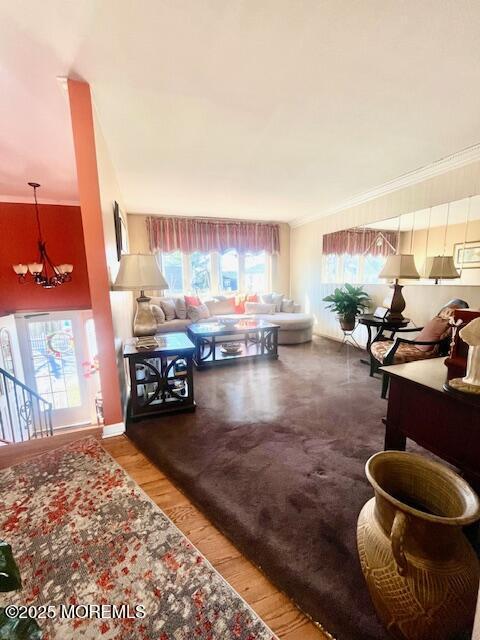 living room with ornamental molding, wood finished floors, baseboards, and an inviting chandelier