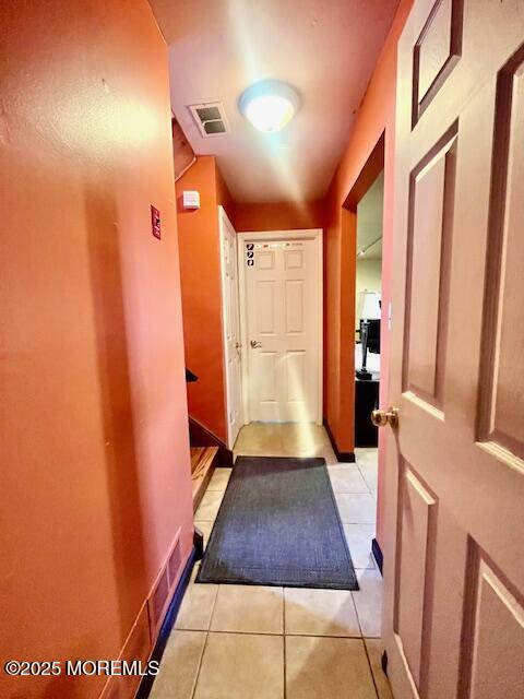 hallway featuring light tile patterned floors and visible vents