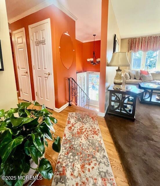 corridor featuring baseboards, a chandelier, wood finished floors, and an upstairs landing