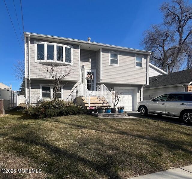 bi-level home with an attached garage, fence, and a front yard