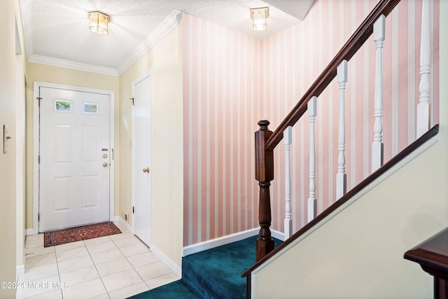 tiled foyer featuring ornamental molding, a textured ceiling, baseboards, and wallpapered walls