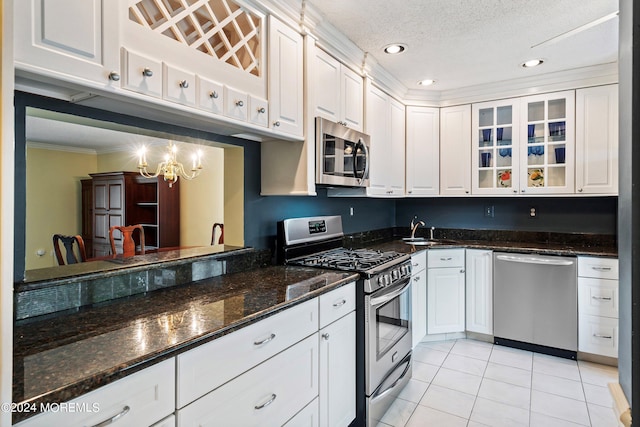 kitchen with appliances with stainless steel finishes, glass insert cabinets, white cabinetry, a sink, and light tile patterned flooring