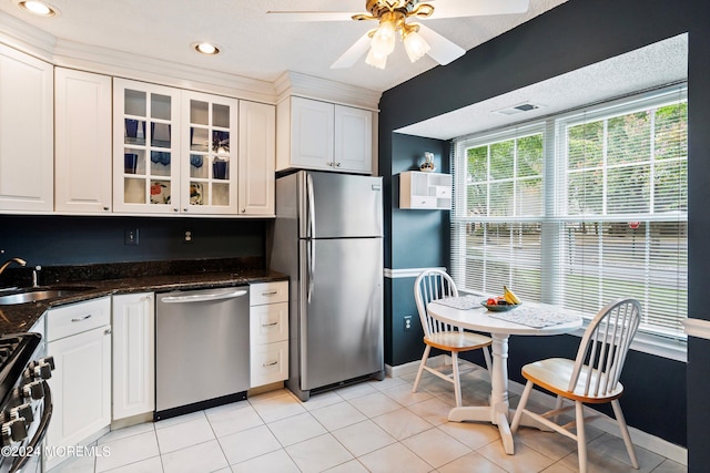 kitchen with stainless steel appliances, glass insert cabinets, white cabinetry, a sink, and light tile patterned flooring