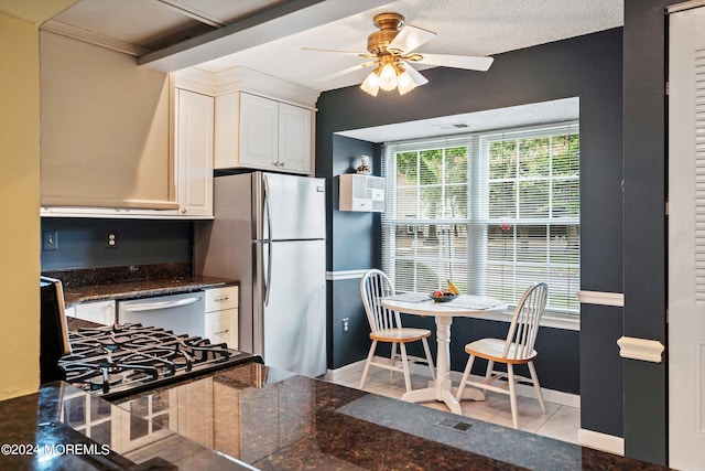 kitchen with dark countertops, appliances with stainless steel finishes, white cabinets, ceiling fan, and tile patterned floors