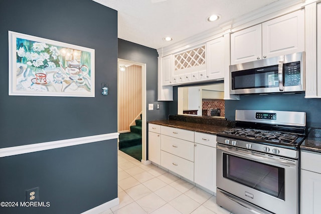 kitchen with tasteful backsplash, dark countertops, stainless steel appliances, white cabinetry, and light tile patterned flooring