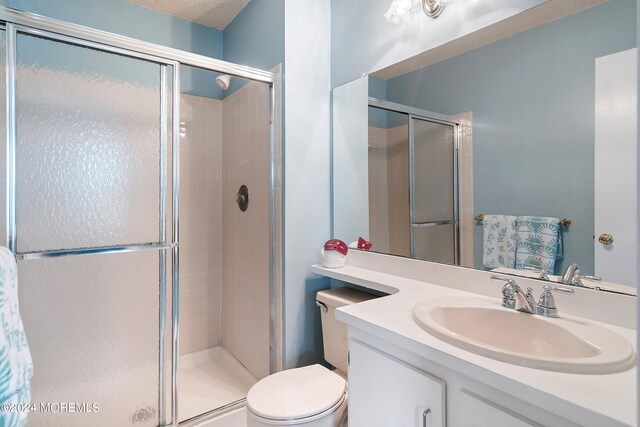 bathroom with toilet, a shower stall, and vanity