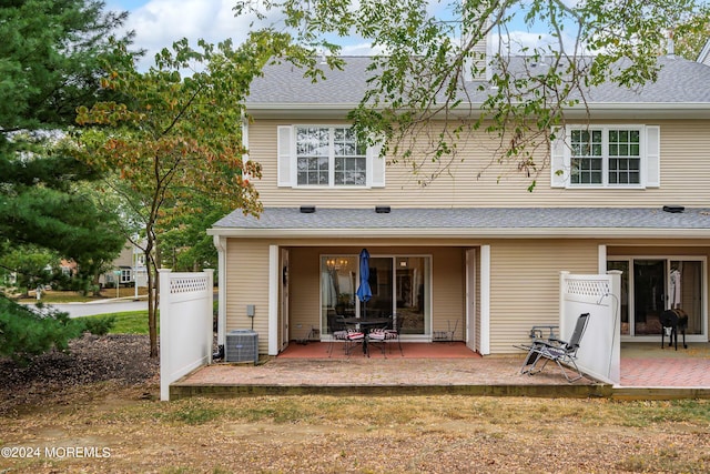 rear view of house with a shingled roof, fence, and a patio