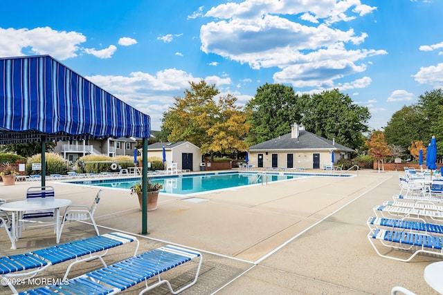 community pool featuring a patio, an outdoor structure, and fence