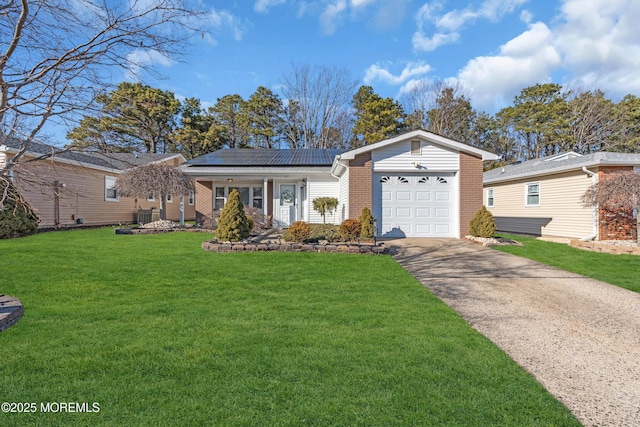 view of front of home featuring a garage, solar panels, brick siding, driveway, and a front yard