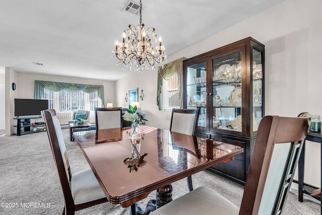 dining area featuring a notable chandelier, visible vents, and carpet flooring