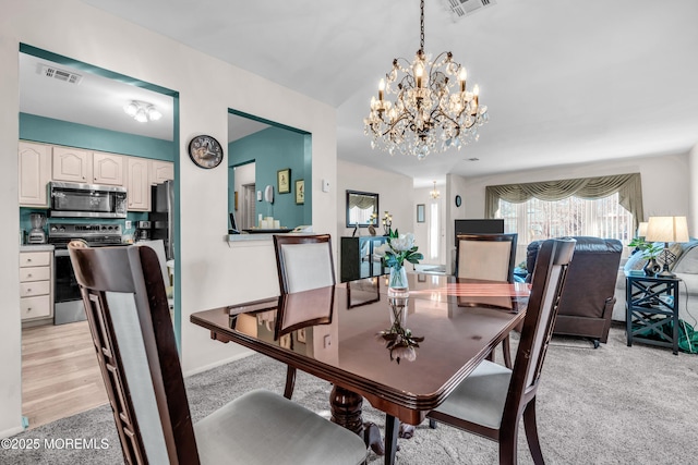 dining room with light carpet, visible vents, and a notable chandelier