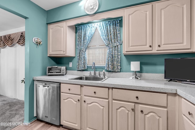 kitchen featuring a toaster, a sink, light countertops, stainless steel dishwasher, and light wood finished floors