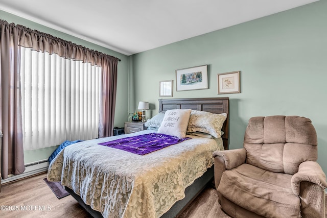 bedroom with a baseboard radiator and wood finished floors