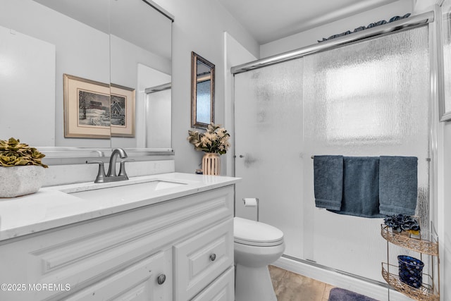 bathroom featuring vanity, a shower stall, and toilet