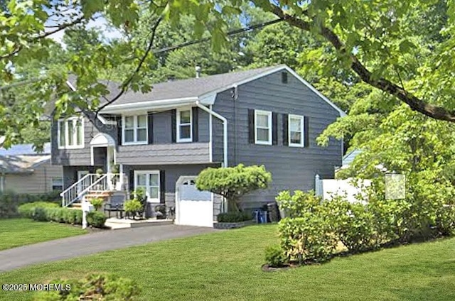 raised ranch featuring driveway, a garage, and a front lawn