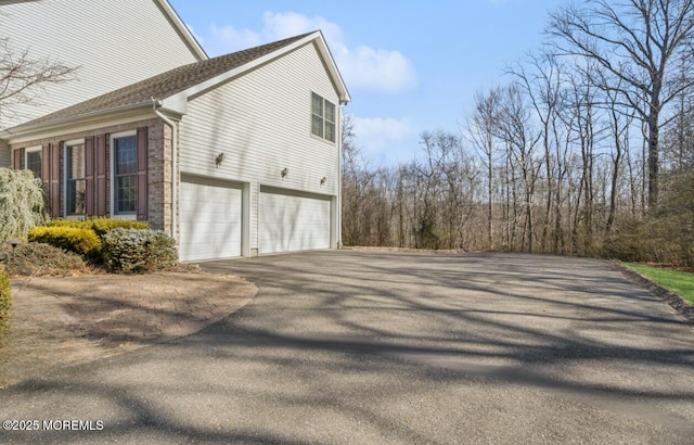 view of side of property featuring a garage, brick siding, and driveway