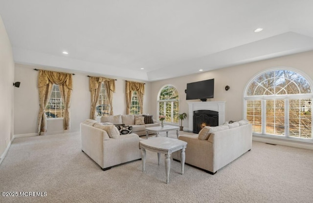 living room featuring a warm lit fireplace, carpet flooring, and recessed lighting