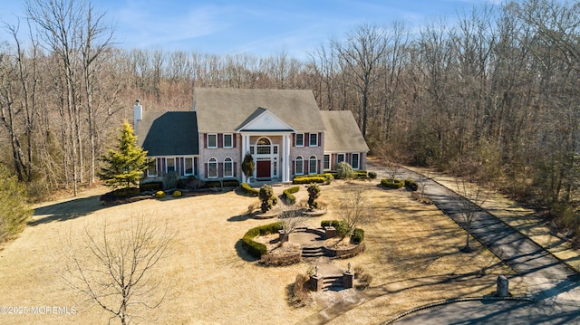 greek revival house featuring a forest view and dirt driveway