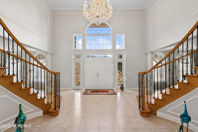 tiled foyer with a chandelier, stairs, and crown molding