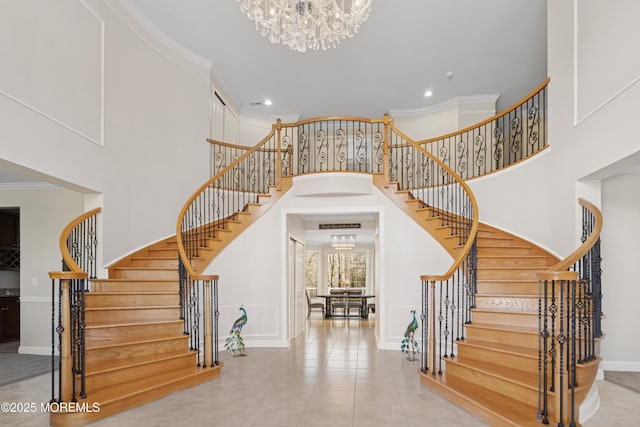 stairs featuring baseboards, a towering ceiling, crown molding, a notable chandelier, and recessed lighting