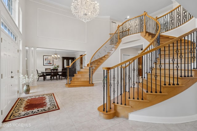 stairway with an inviting chandelier, a high ceiling, crown molding, and ornate columns